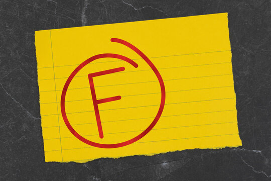 Grade F with circle on a white lined torn paper on black stone