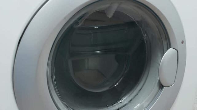 Water fills the washing machine drum during the laundry process. This is the washing cycle at home.	