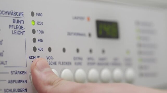 Close-up of a person's hand pouring detergent and turning on a washing machine, selecting a program mode and pressing the "Start" button on the control panel.	
