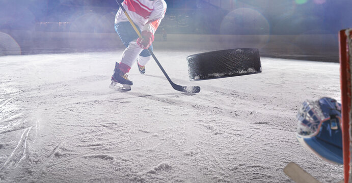 Ice hockey rink arena with professional player shooting the puck with hockey stick.