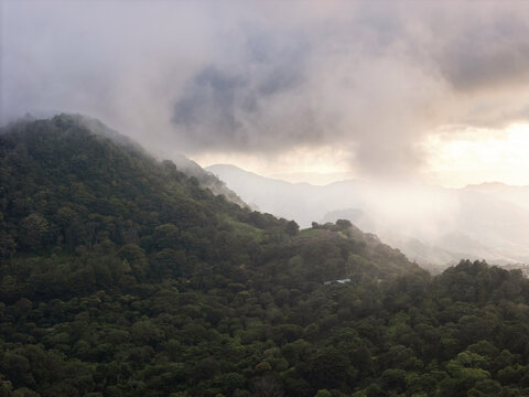 Fog covers hills as sunlight peeks through clouds during late afternoon