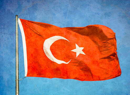 Grunge image of Turkish flag waving in the sky.