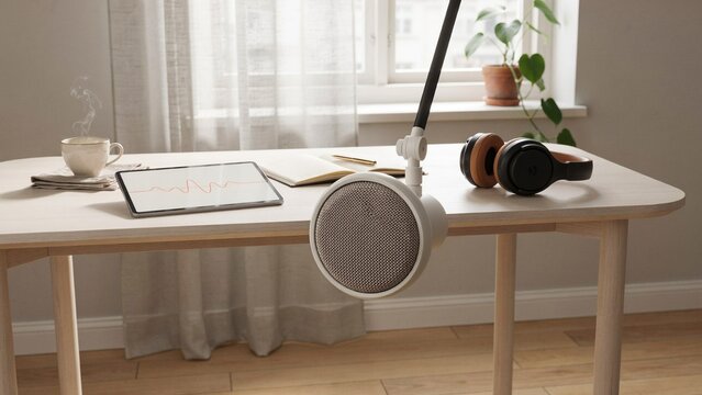 Minimalist home office desk with professional microphone, digital tablet and headphones. Bright scandi workspace for podcasting.