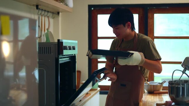 Young Man Baking Cookies at Home Kitchen with Oven Mitts and Stand Mixer