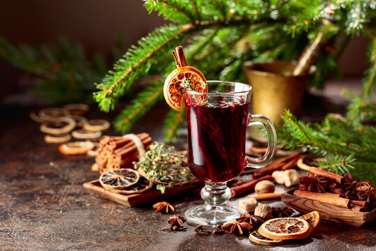 Mulled wine with spices and dried citrus on a brown vintage background.