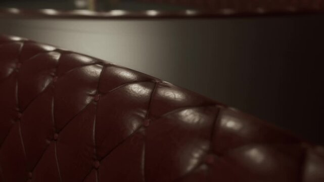 Rich burgundy leather seats fill an intimate dining space, creating a warm atmosphere. Shiny textures and gentle contours invite patrons to enjoy their meals in comfort and privacy.