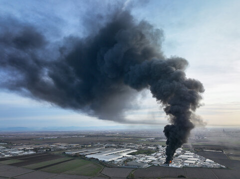 Aerial view of a large column of black smoke rising from a fire at a chemical plant in an industrial area of Novara, Piedmont, Italy.