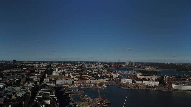 Drone view of Helsinki city center showing a large cluster of construction cranes along the waterfront with modern buildings harbor facilities and ongoing urban redevelopment
