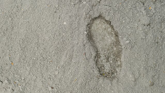 Gray gravel and sand ground texture with foot print sign
