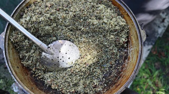 Huge cauldron with fried rice and metal spatula at outdoor street food market. Traditional asian cuisine cooking in large pot. Street food festival concept