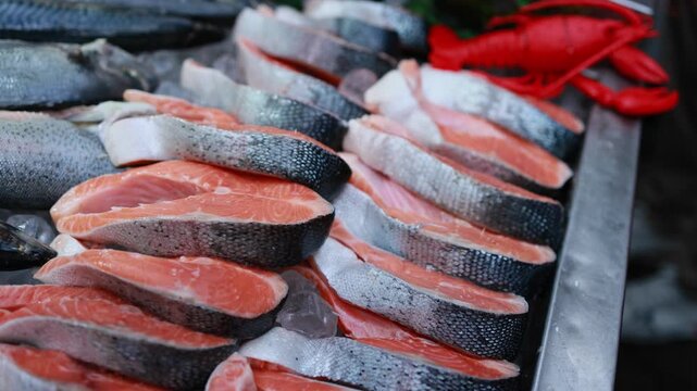 Fresh salmon steaks on ice at fish market counter. Raw red fish fillets with skin displayed in seafood store. Healthy food and grocery shopping concept.