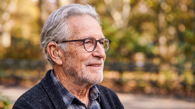 Senior man with hearing aid and glasses enjoying active lifestyle outdoors