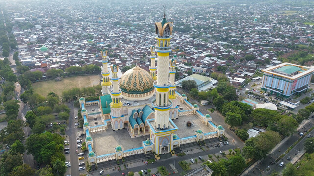 Aerial view of the Hubbul Wathan Grand Mosque with its distinctive central dome and tall minarets surrounded by urban landscape in Indonesia.