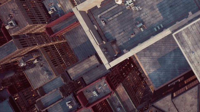 Looking down at a bustling city, rooftops and buildings create a maze of structures. The view highlights the vibrant energy and architectural beauty of urban life during the day.