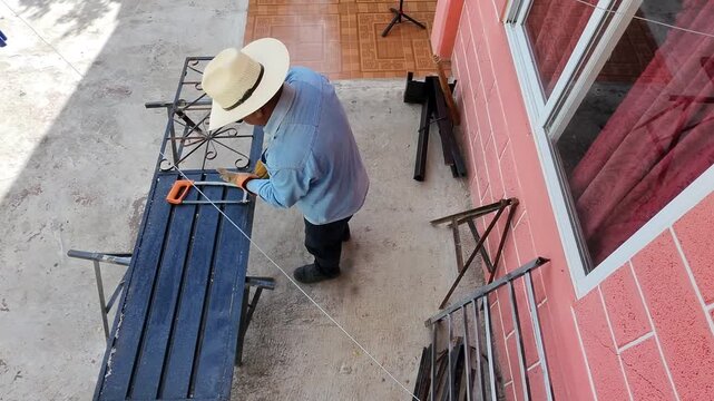 Drone filming a blacksmith wearing a hat putting on work gloves.