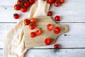  Fresh cherry tomatoes whole and halved on a wooden cutting board