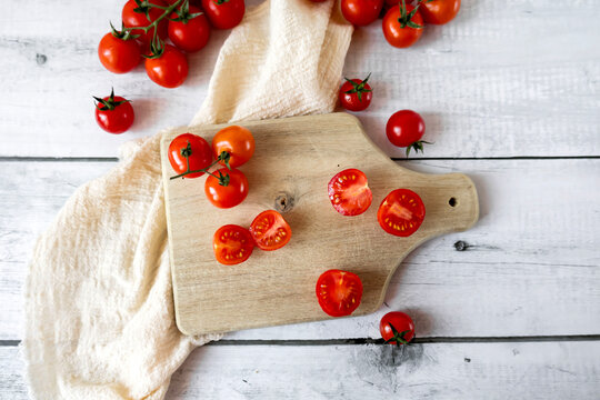  Fresh cherry tomatoes whole and halved on a wooden cutting board