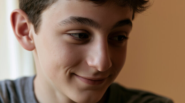 Young person smiling with eyes downcast in warm indoor lighting