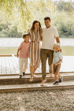 Family enjoying a joyful walk by the serene lakeside during golden hour