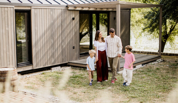 Family enjoying a sunny day by a modern cabin near the water