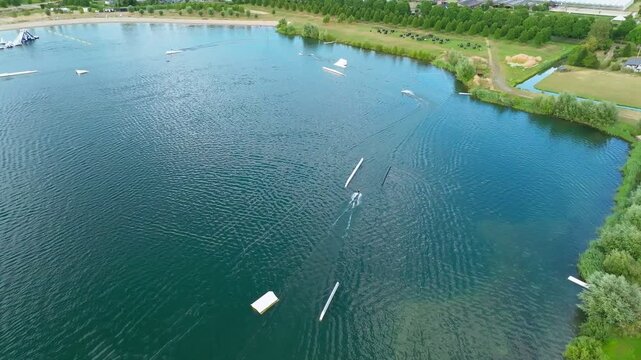 Aerial view of a cable water ski park lake with jumps, obstacles and a rider training on a lake