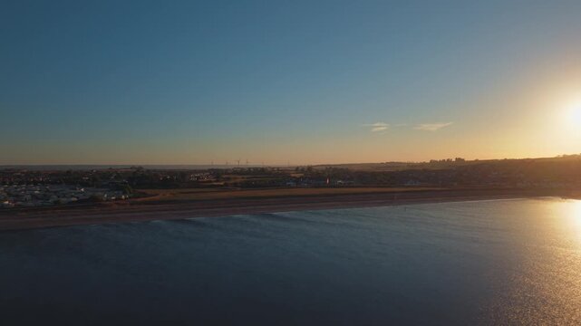 Isle of Sheppey, Leysdown Beach coastline after the solar eclipse, with the sun above the horizon and seaside below, wide aerial panorama