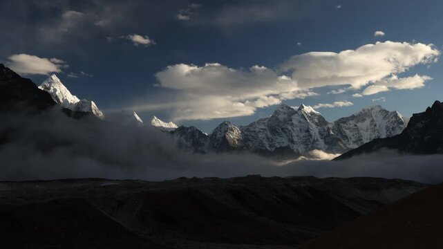 Timelapse of a dramatic Himalayan mountain landscape in Nepal, with rugged peaks and valleys changing under moving clouds and evening light.