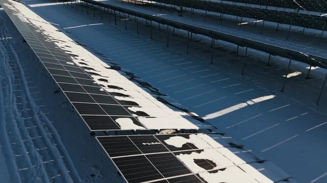Snow partly covers dark solar panels, revealing variable winter generation