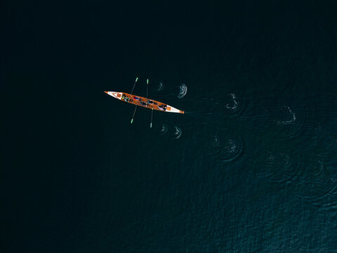 Aerial view of a rowing boat with rowers moving across the dark water, Copenhagen, Denmark.