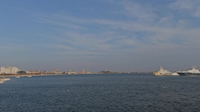Wide static shot of an Istanbul waterfront showing harbor buildings moored yachts and a calm sea under a hazy sky
