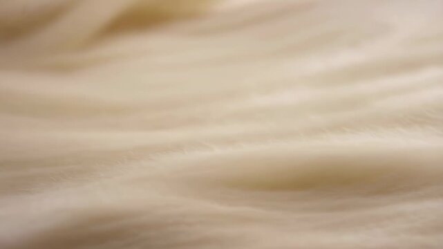 Soft cream and beige fiber-like bands ripple laterally across a minimal abstract field. Fashion branding, beauty advertising, and luxury product promotion.