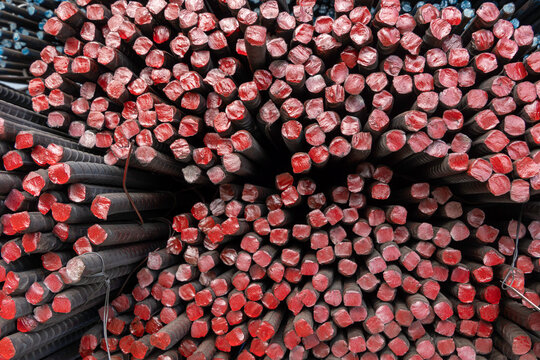 Stack of deformed steel rebars with red painted ends in warehouse