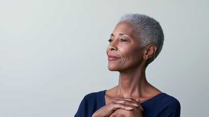 Obraz premium Woman with short gray hair smiling upward with hands clasped