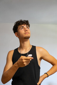 Young person using a remote control to operate a home appliance while looking up at the ceiling