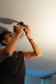 Young person using a electric screwdriver for a ceiling installation
