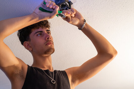 Young electrician doing electrical installation on the roof of a house using pliers