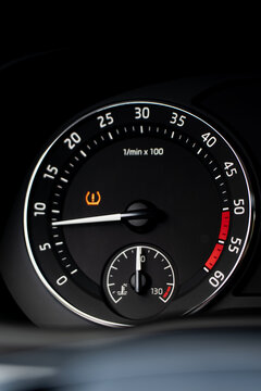 Car tachometer displays an illuminated tire pressure warning above a coolant temperature gauge, illustrating dashboard alerts and engine operating information for drivers
