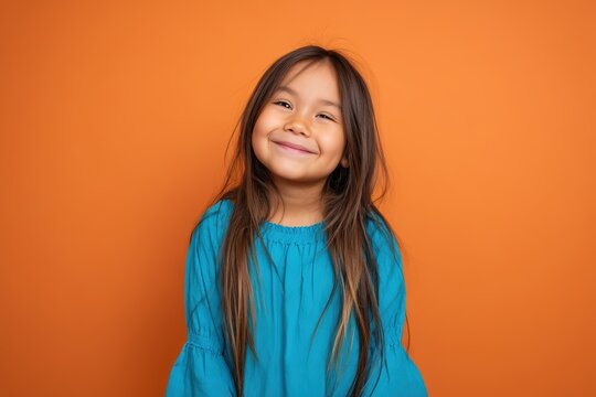 Happy child portrait of a smiling girl on solid orange backdrop