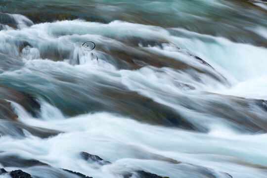 Canada, Alberta, Banff.  Turbulent waters flow over an abandoned bicycle in the Bow River Falls.
