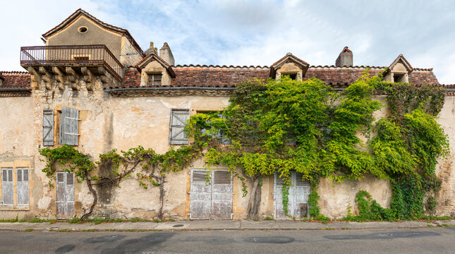 France, Lot, Bretenoux.  House fa&ccedil;ade with shuttered doors and windows, overgrown with wisteria.