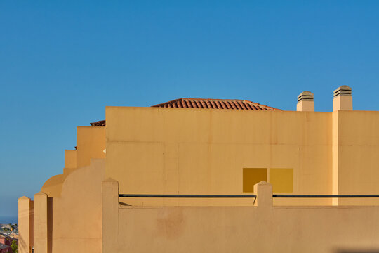 Minimalist architectural composition showcasing building facades, terracotta roof tiles, and clean lines under bright sunlight.