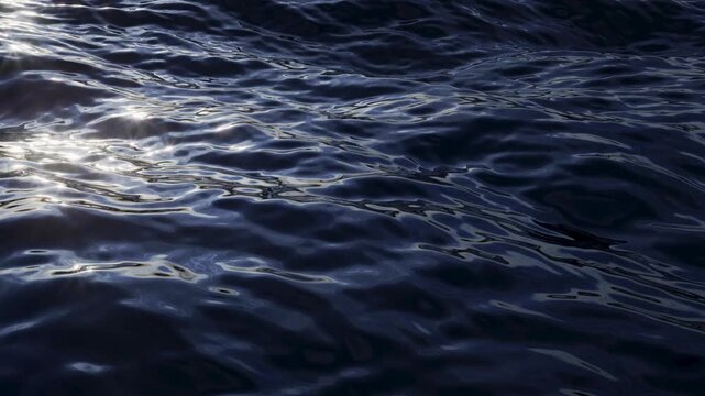 Dark ocean waves roll with glossy caustic highlights. Seamless loop for cinematic water backgrounds, branding, and motion design. 3d render motion.