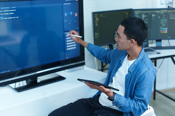 Fototapeta premium Programmer Analyzing Code and Digital Data on Multiple Screens