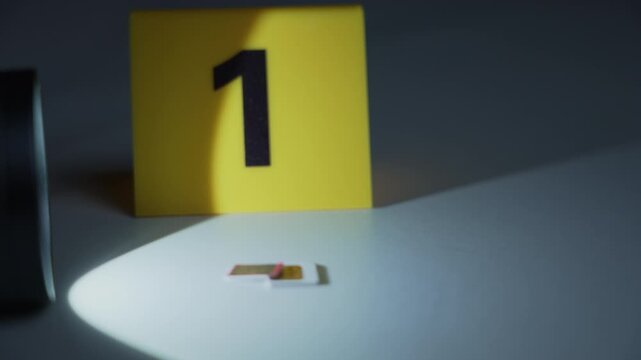 SIM card and evidence marker one under flashlight beam, focus shift from chip to marker with slow zoom in, cybercrime forensic investigation