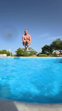 Man jumping into a clear blue outdoor swimming pool on a sunny summer day, captured in dramatic super slow motion at 240 fps.