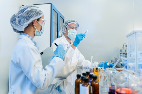 🔬 Professional Lab Scene: Two Dedicated Researchers in Full Protective Gear In a prist. Asian scientists or researchers team working on medical and pharmaceutical development in a modern laboratory.