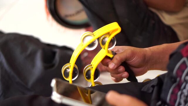 A person typing on a smartphone with a yellow tambourine instrument resting on their lap.