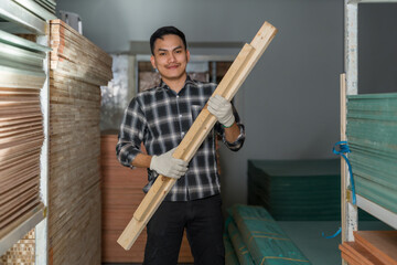 Asian adult male carpenter standing and presenting wooden planks with confident posture,...