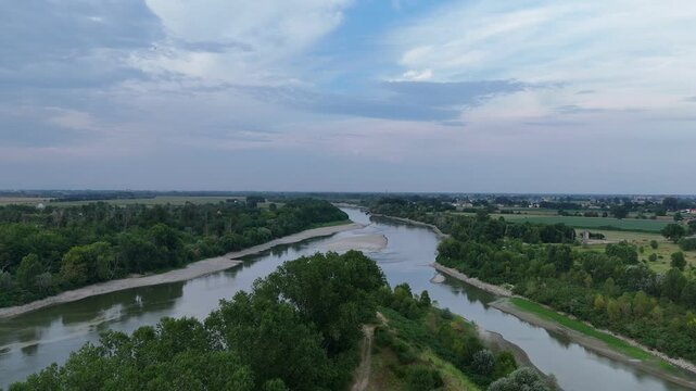 Po River near Isola Serafini shows exposed sediment and reduced flow between wooded banks and farmland along the Emilia-Romagna and Lombardy border, drone static shot