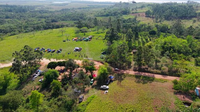 Right panning aerial view tracking fast rally car leaving dust trail on dirt roads while a media coverage helicopter follows trackside. Recorded on 4K at 24 fps.